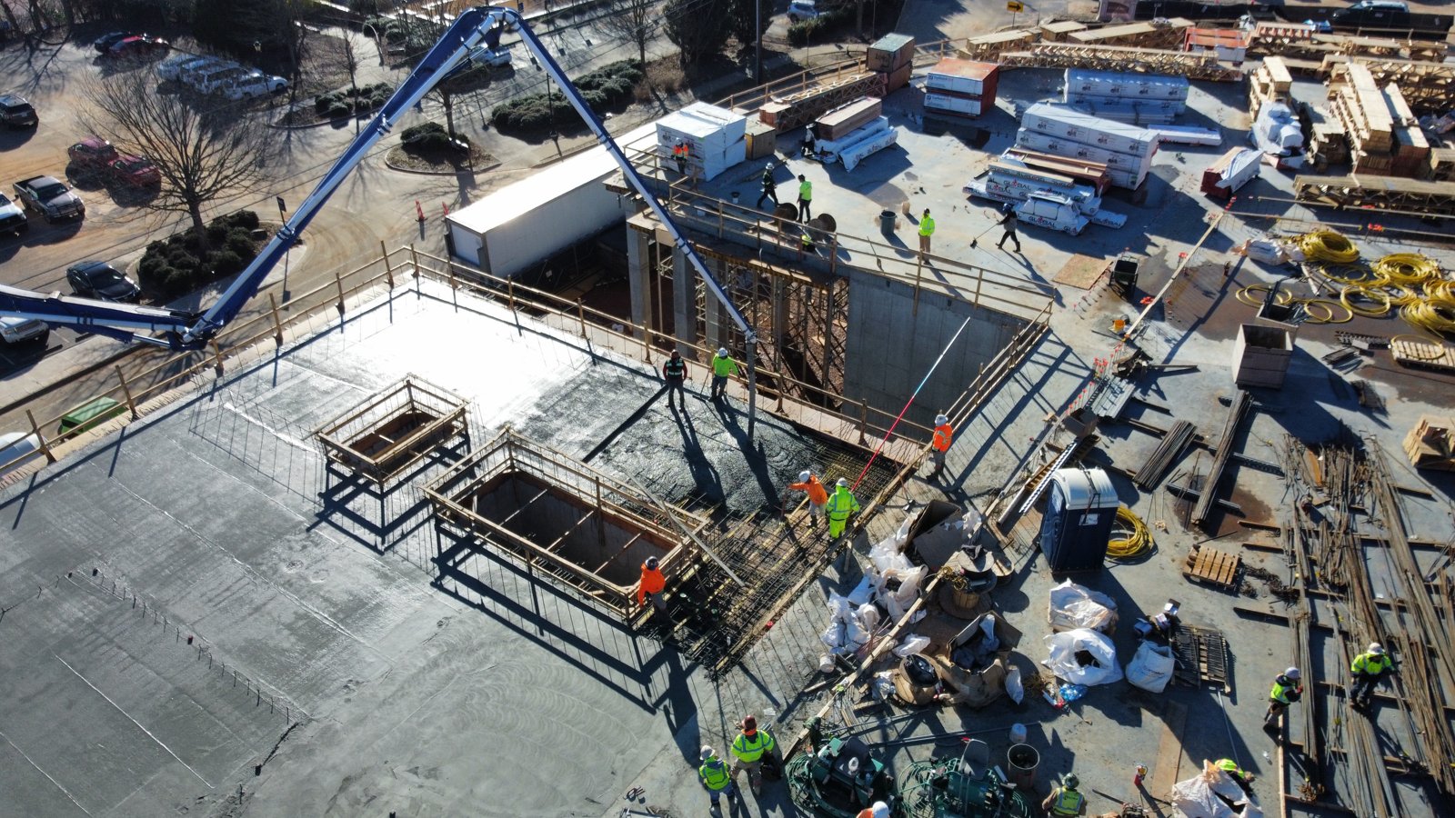 Aerial view of an elevated podium deck concrete pour with tower crane and placing boom