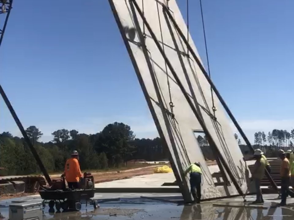 Crane lifting a tilt-up concrete wall panel into place