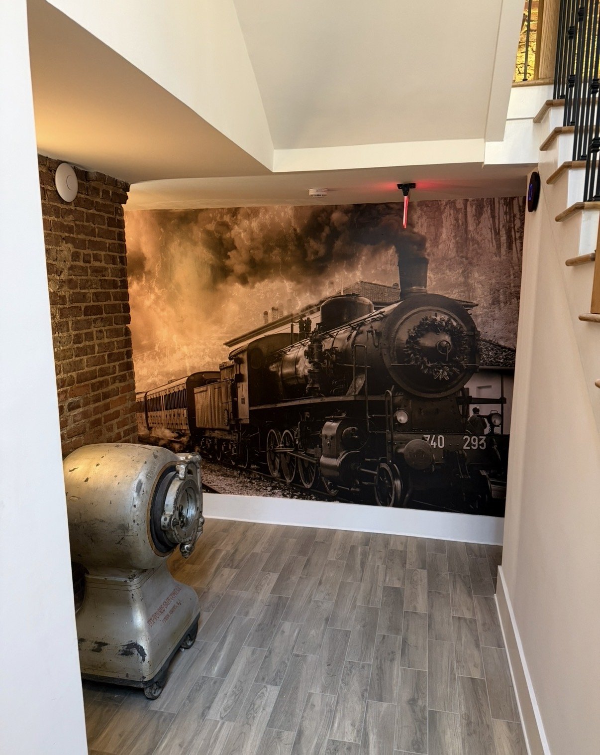 Curated interior nook with heritage railroad mural, exposed brick, and vintage machinery